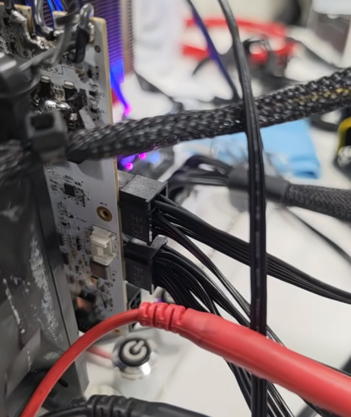 A close-up of a computer motherboard with multiple power cables connected, including red and black braided cables.